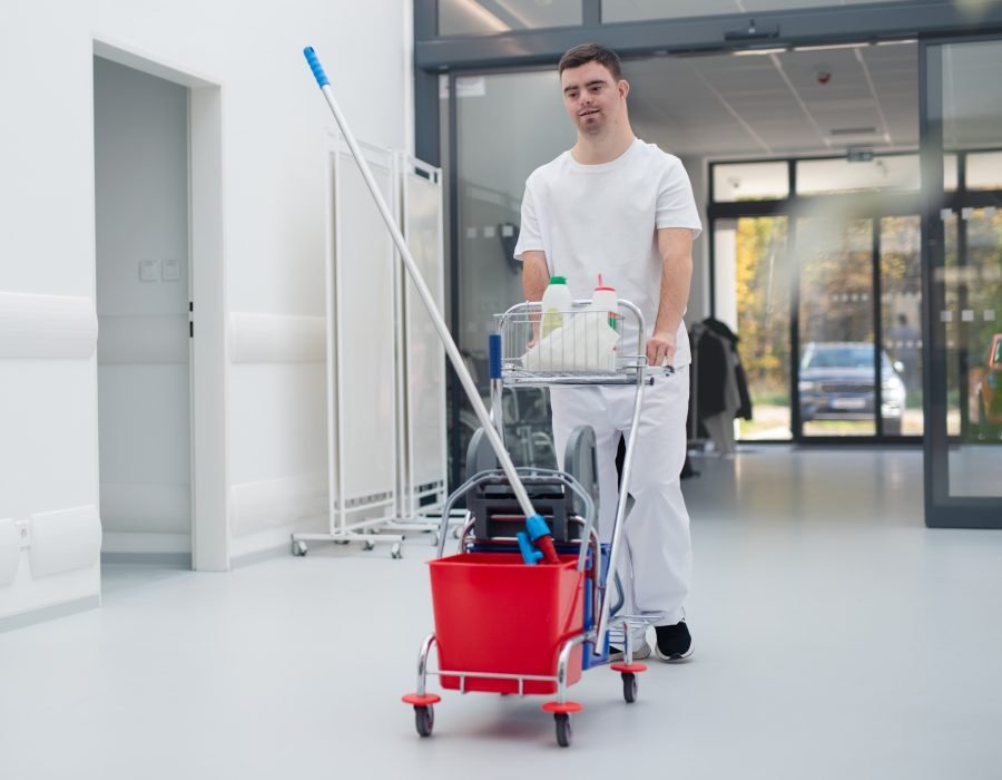 Young man with down syndrome working in a hospital as cleaner. Concpet of integration people with